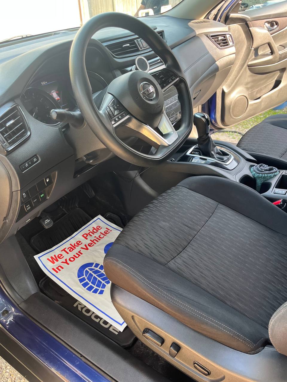 The same Nissan Rogue footwell after cleaning, with the mat and sill clean and a protective paper mat laid down