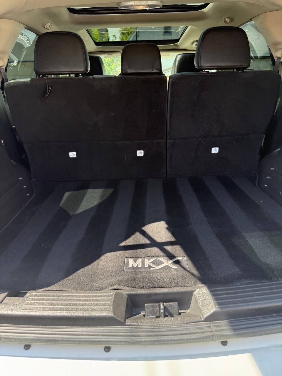 The same MKX cargo area after cleaning, framed close, with fresh vacuum lines across the carpet and the MKX sill mat